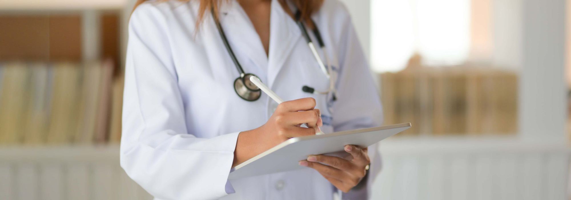 Cropped shot of young doctor checking patient chart while using digital tablet