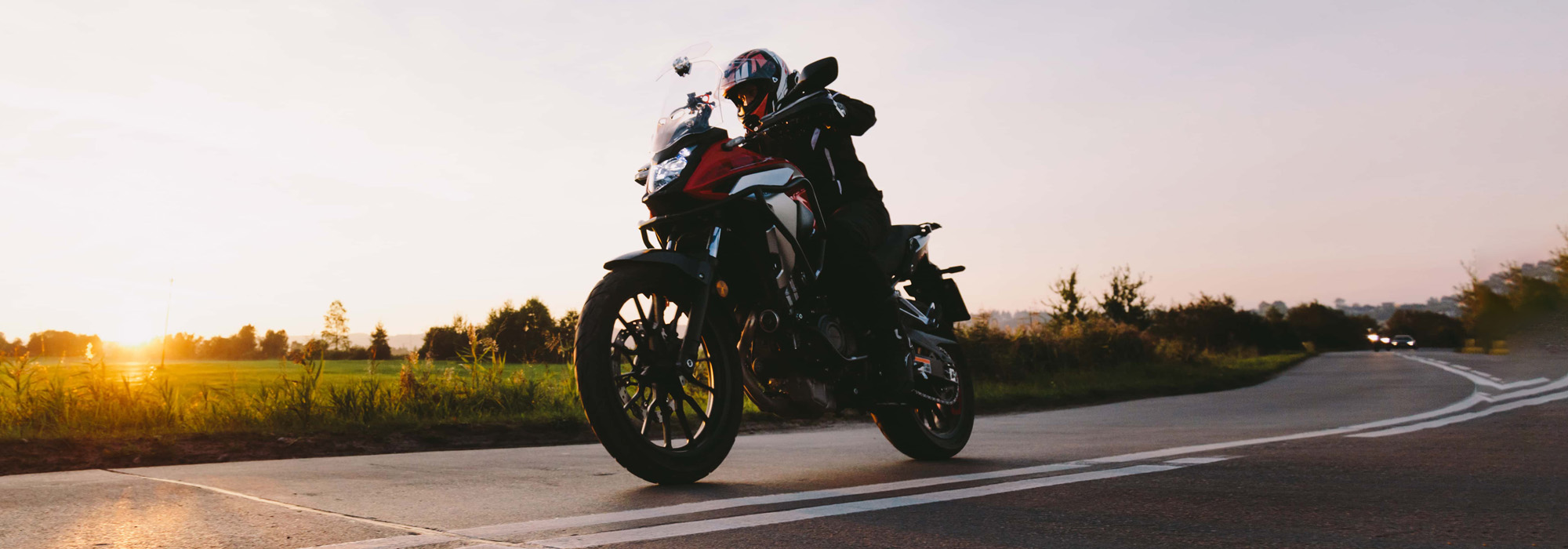 Fast motorcycle drive on asphalt road at sunset