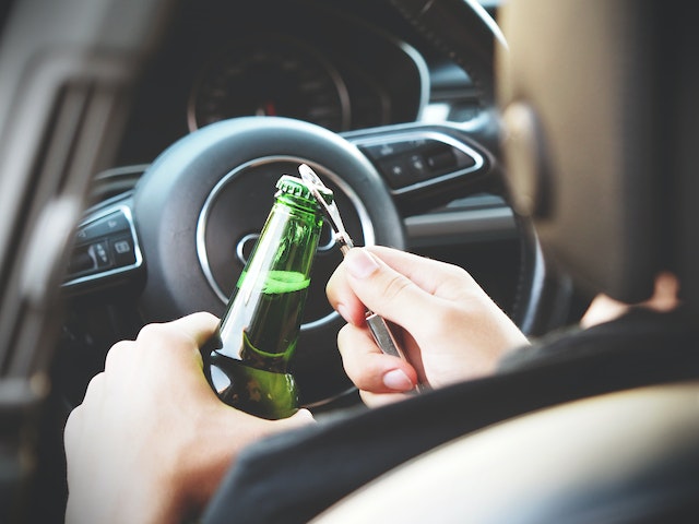 person opening beer bottle behind wheel