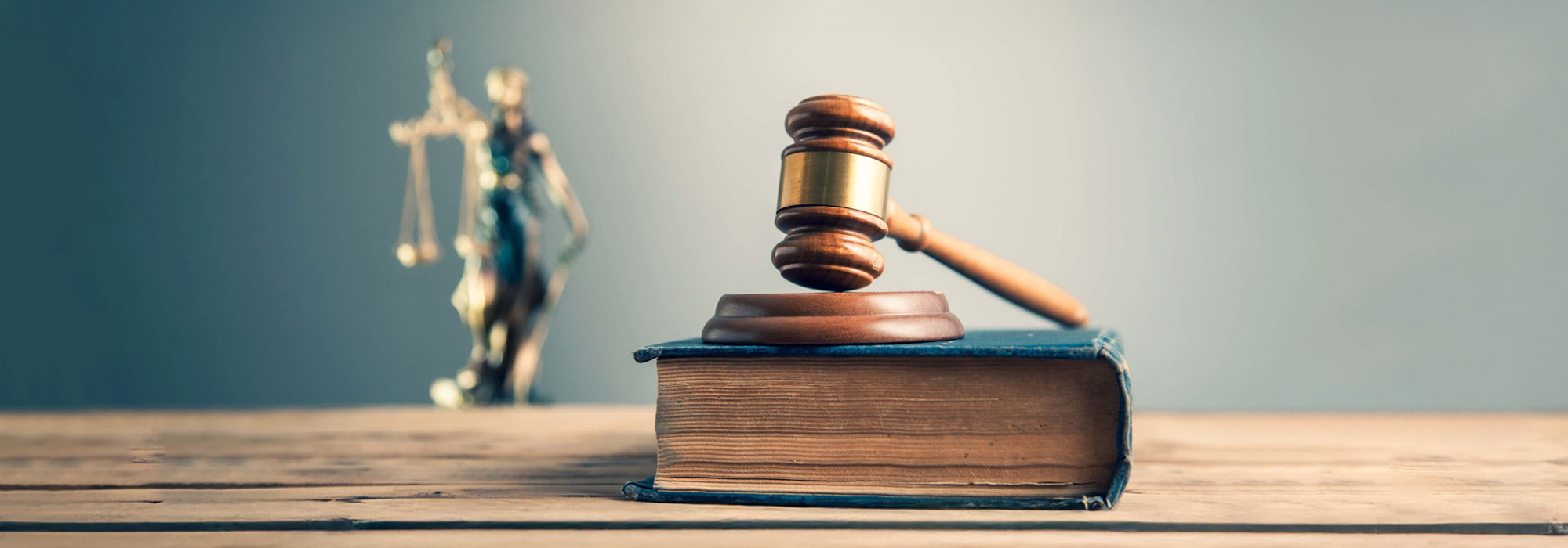 wooden judge on book with justice lady on desk