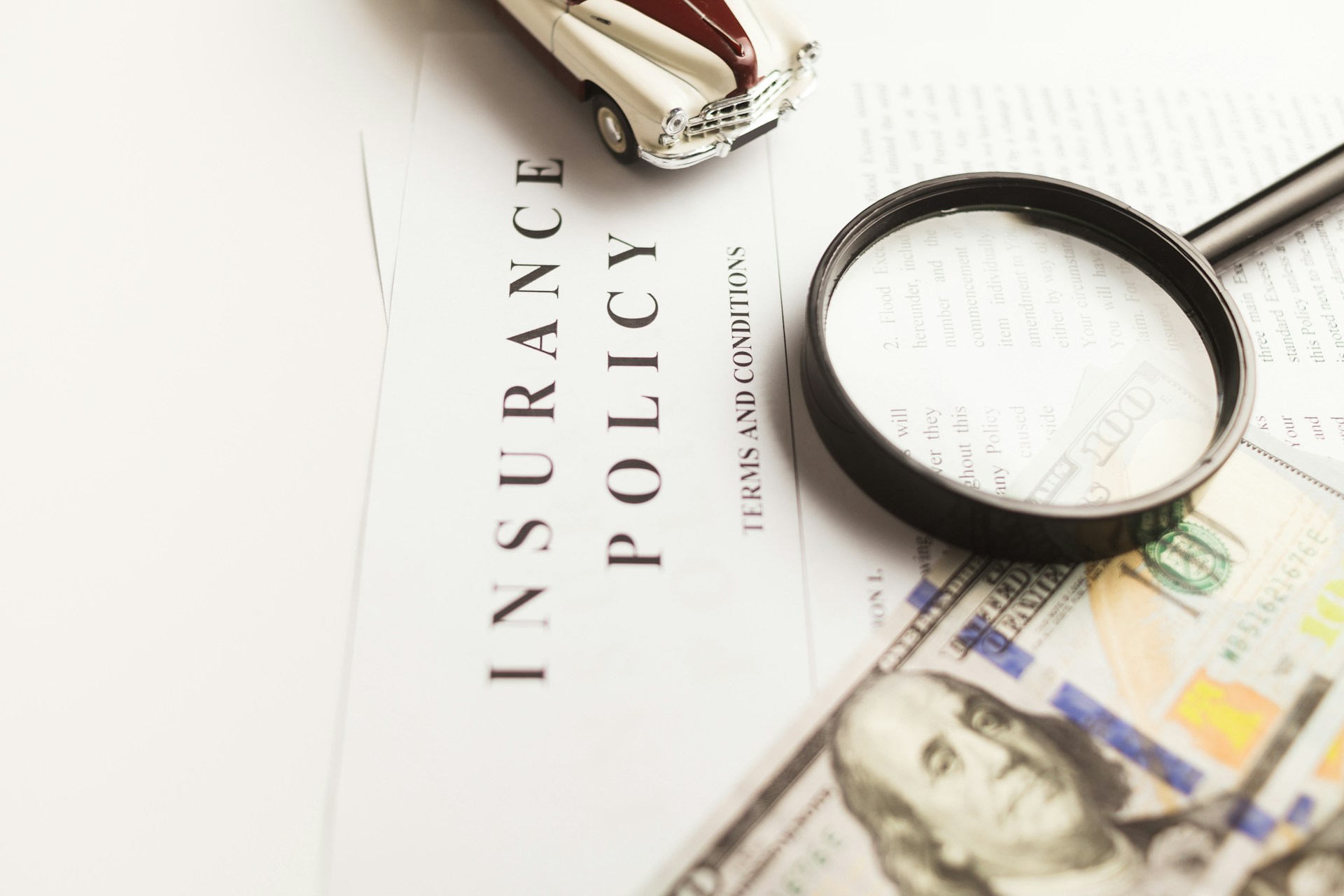 insurance policy, magnifying glass, miniature car